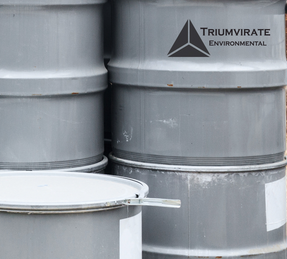 Gray 55 gallon drums with Triumvirate Environmental logo