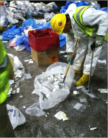 Worker in white PPE suit safety vest and helmet handles thrash