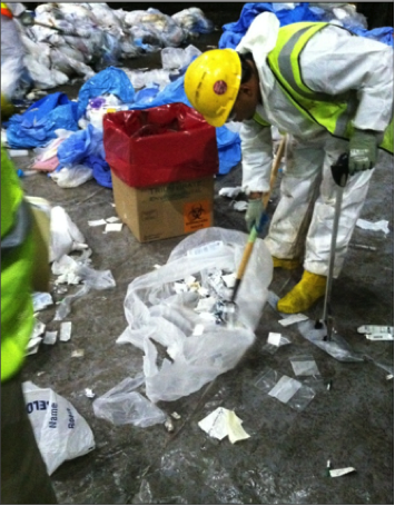 Emergency response worker in PPE gathers waste
