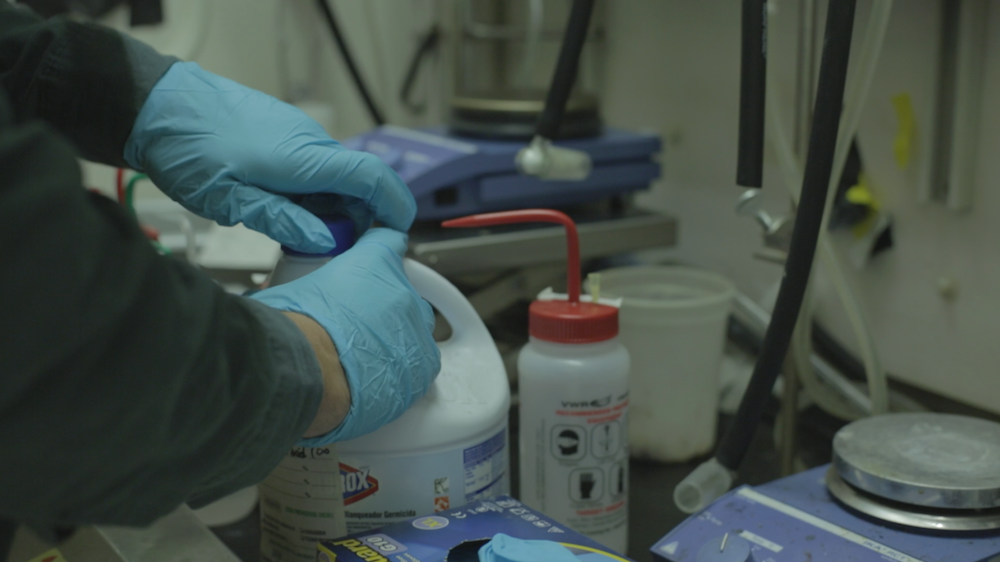 Lab decontamination worker prepares chemical container 
