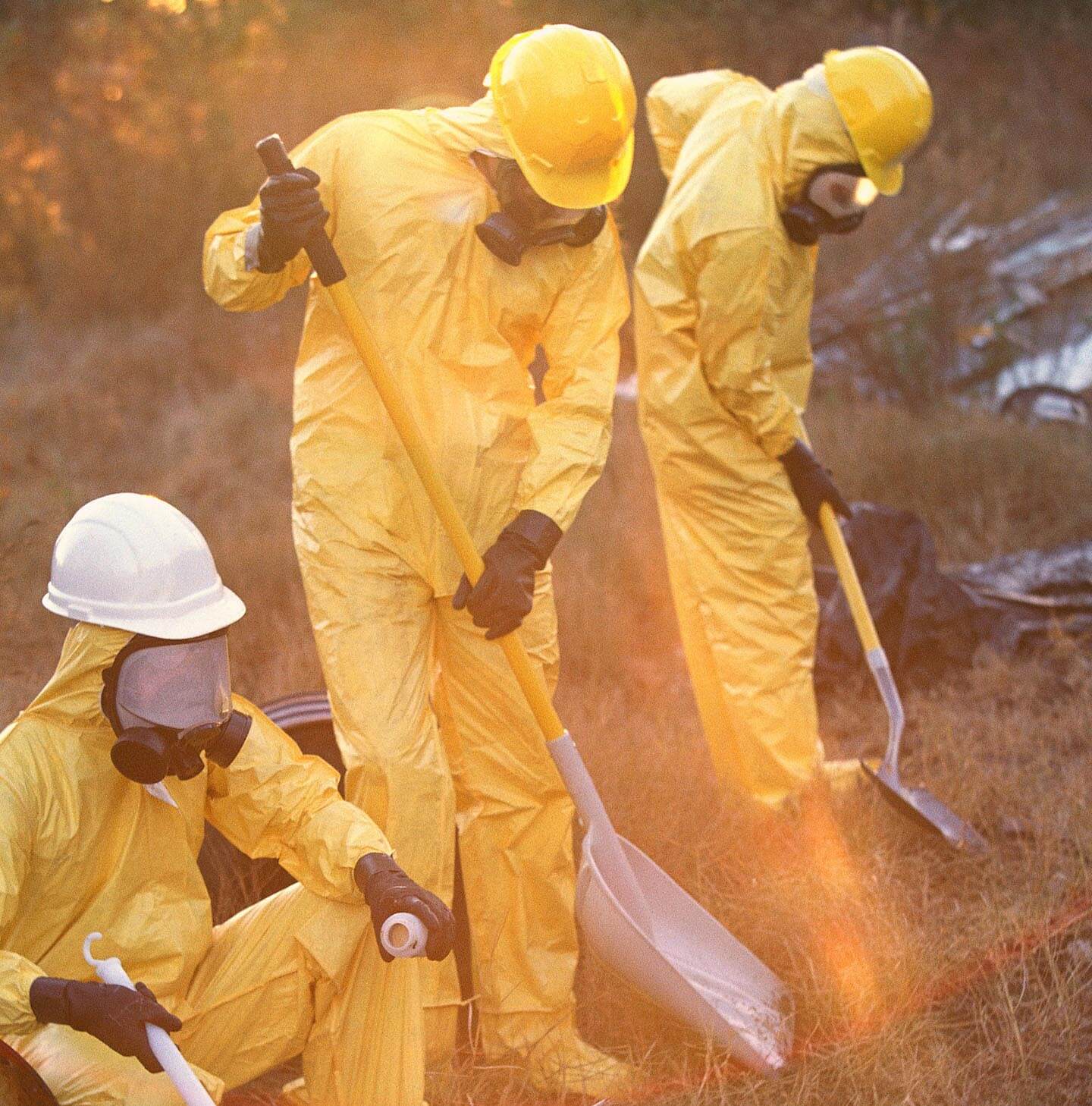 Workers in yellow hazmat suits working soil