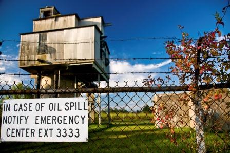 Oil spill warning sign outside fenced in facility