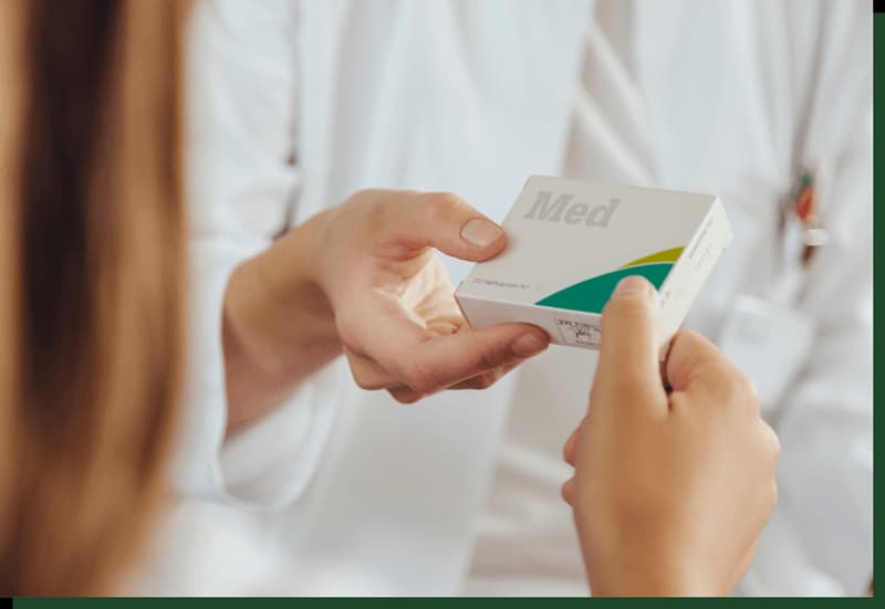 Pharmacist handing a box of medicine to a patient.