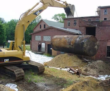 Construction machine raises underground storage tank from ground