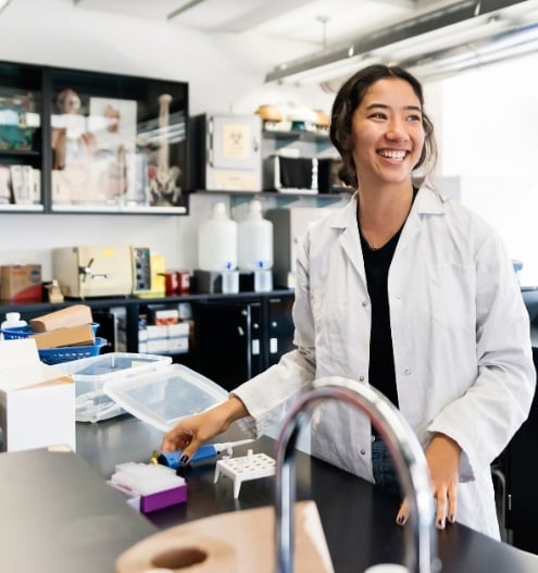 smiling university student wearing a lab coat in a school laboratory