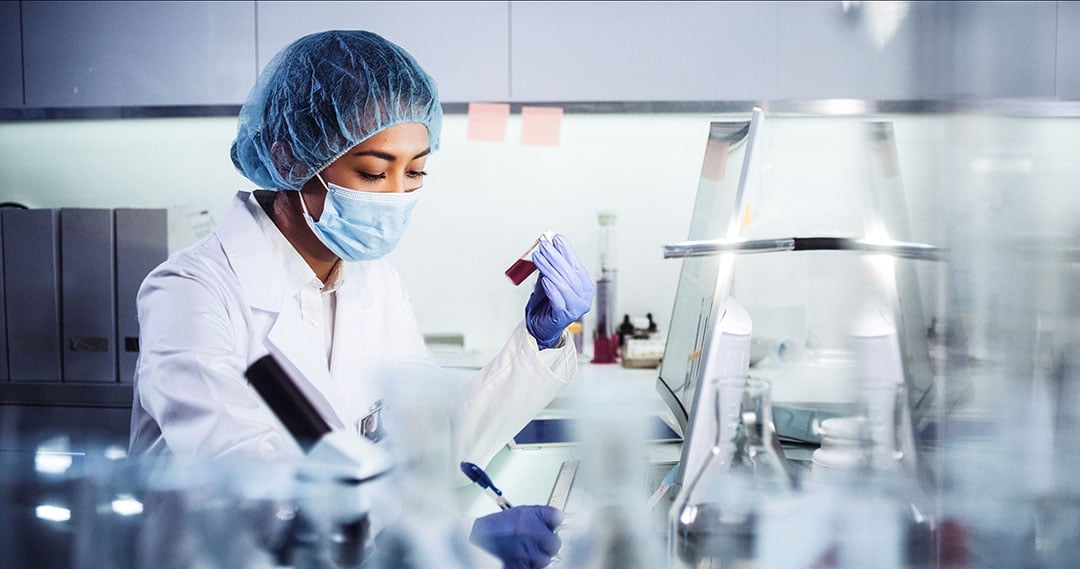 Laboratory professional examines a biological sample while following biosafety procedures in a research laboratory.