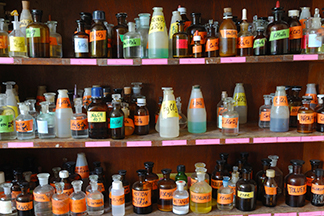 Four shelves of chemical bottles in a flammables cabinet