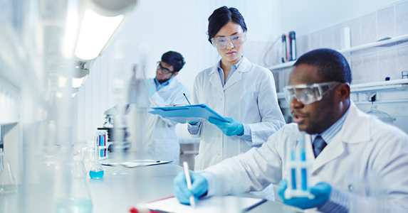 Team of scientists working in a lab with safety goggles and gloves