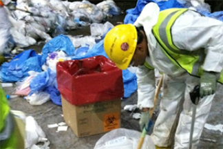 An emergency responder wearing a yellow vest cleans up hazardous waste in response to an emergency