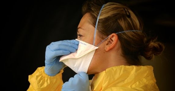 woman wearing gloves, protective suit and ppe mask