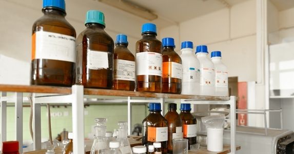 Brown and white chemical bottles lining laboratory shelf