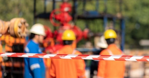 workers in hardhats behind caution tape