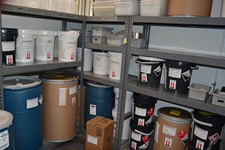 Hazardous waste storage room with drums, buckets, and containers