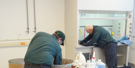 Two laboratory relocation team members clean thrash and counters