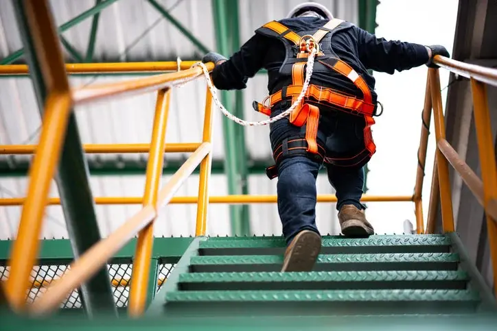 Man walking up ladder with fall protection safety. 