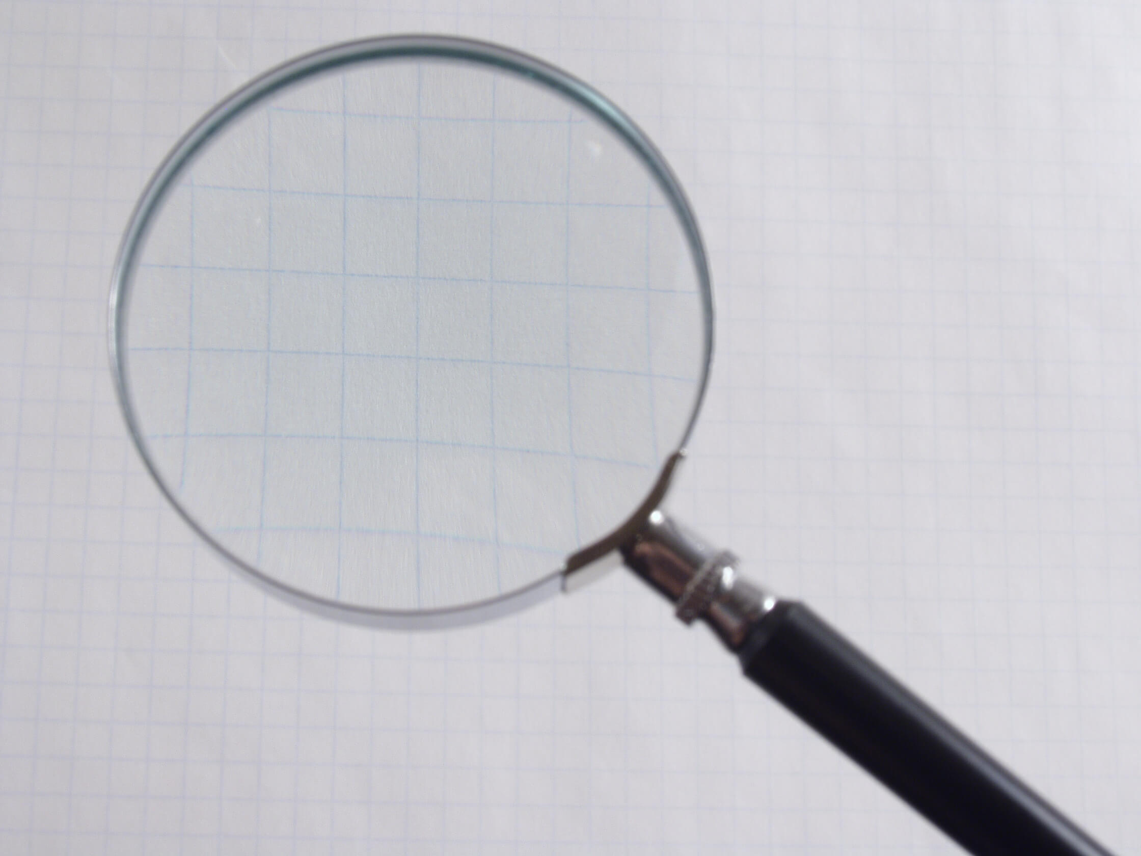 Large magnifying glass over grid paper