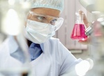 Lab worker in safety glasses analyzes small beaker