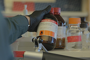 Gloved scientist examines a chemical bottle during a chemical reconciliation