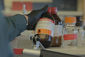 Gloved scientist examines a chemical bottle during a chemical reconciliation